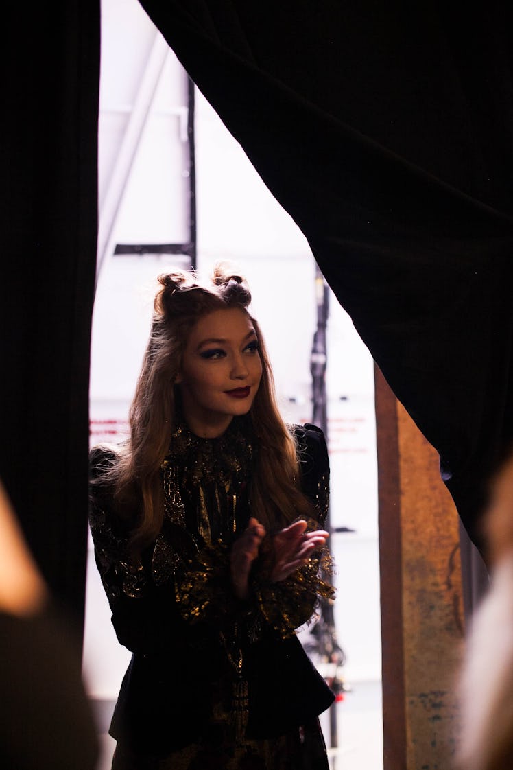 Gigi Hadid applauding in a sequin jacket and a double knot backstage at a fashion show