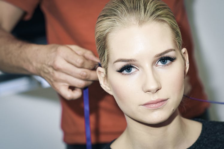 Lottie Moss looking at the camera while a hairdresser is preparing her hairstyle