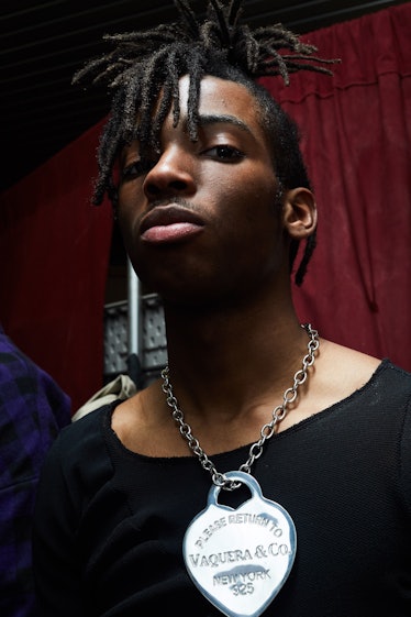 A male model posing with a silver Vaquera & Co chain necklace while wearing a black shirt