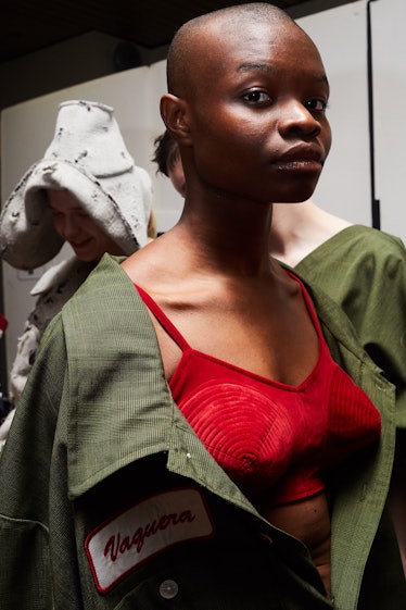 A female model posing while wearing a green shirt over a red bra