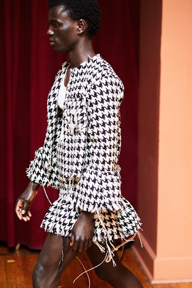 A model walking while wearing a black and white blazer and skirt combination