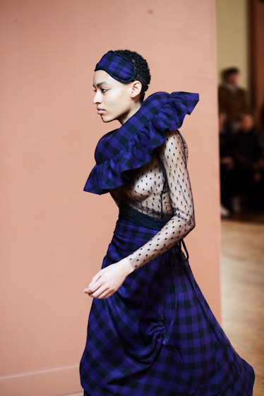A female model walking while wearing a black and blue plaid gown