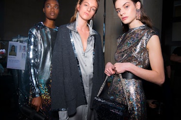 A model in a silver sequin dress, in a grey-white coat and a silver dress at the Christopher Kane Fa...