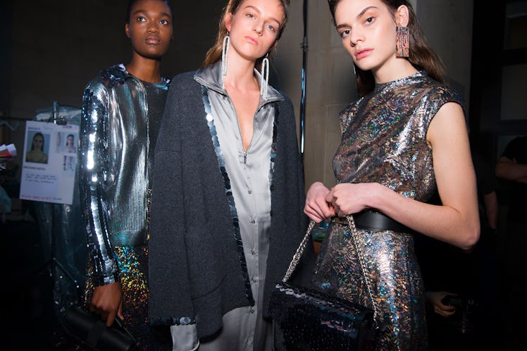 A model in a silver sequin dress, in a grey-white coat and a silver dress at the Christopher Kane Fa...