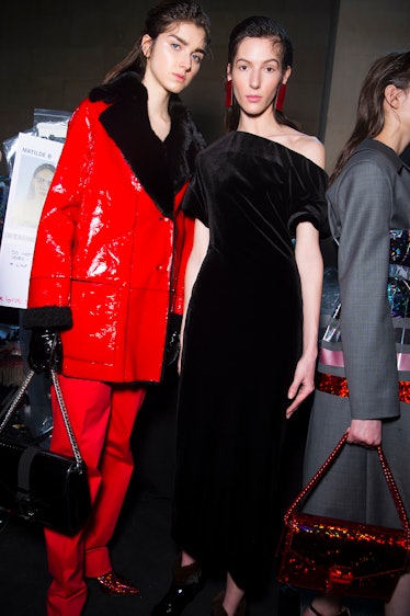A model in a red suit with black collar and a model in a black velvet dress at the Christopher Kane ...