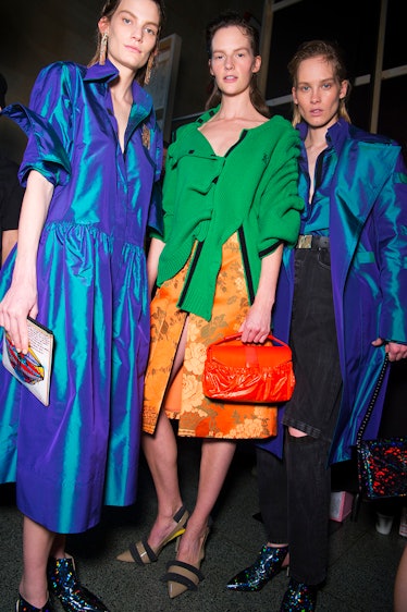 Two models in blue dresses and a model in a green top and orange skirt at the Christopher Kane Fall ...