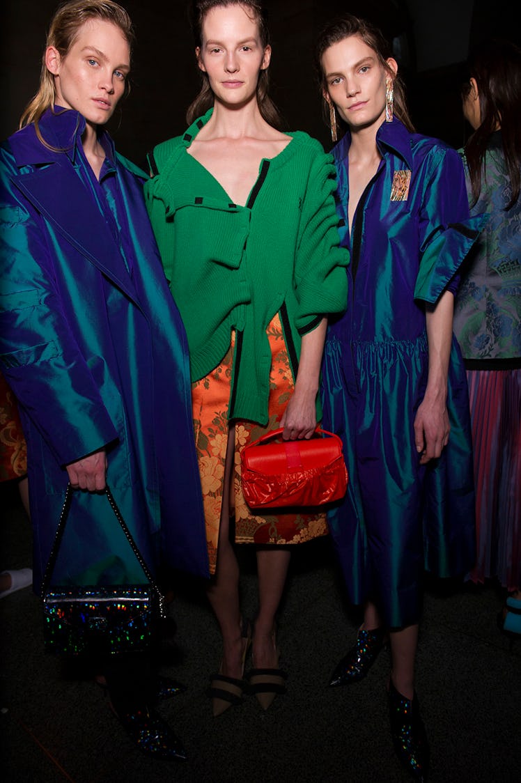 Two models in blue dresses and a model in a green top and orange skirt at the Christopher Kane Fall ...