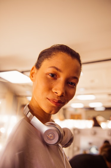 A female model posing while wearing white headphones hanged around her neck