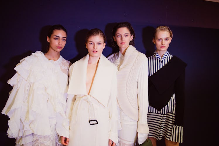 Four female models in white outfits posing for a photo at the backstage at Burberry Fall 2017 show