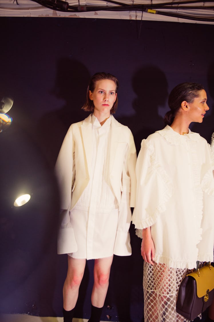 Two women standing next to each other while wearing white dresses