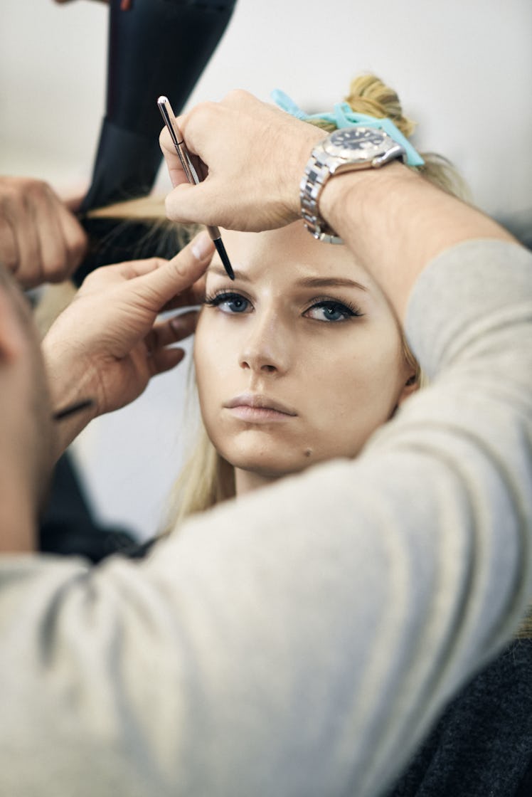 Makeup artist preparing Lottie Moss for a show
