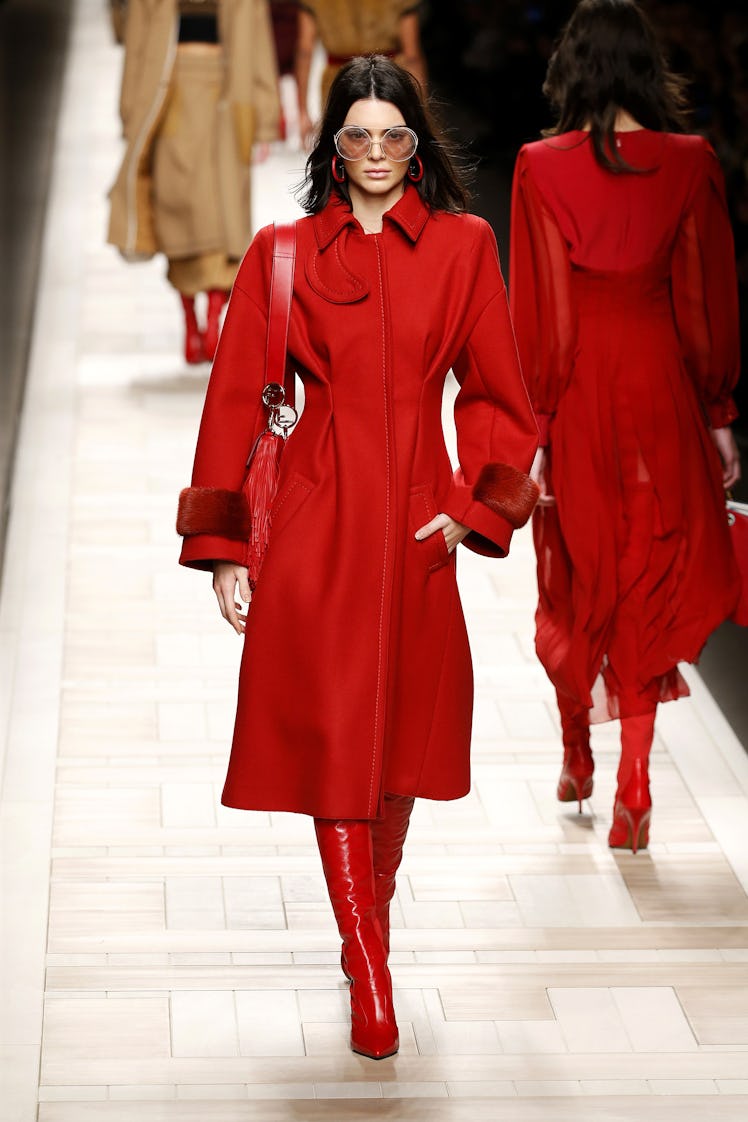 A female model walking in a red Fendi coat