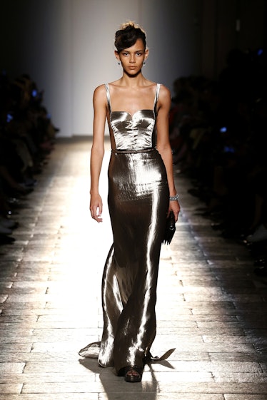 A female model walking a runway in a silver Bottega Veneta gown