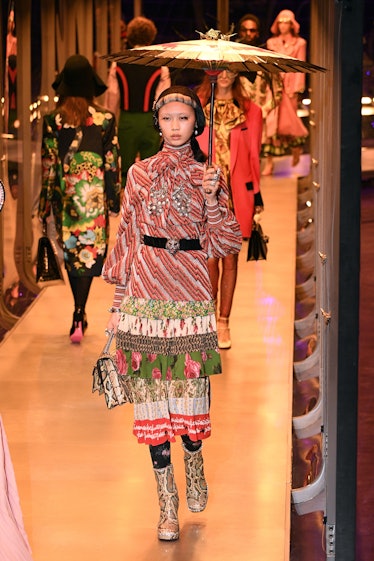 A female model walking with two Gucci bags