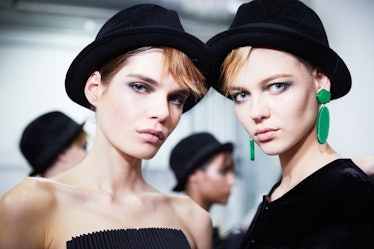 Two models with black hats posing for a photo