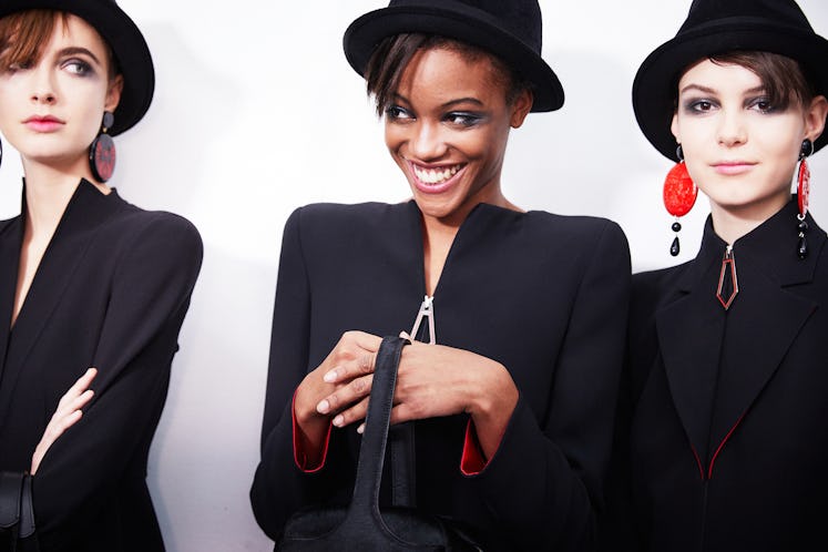 Three female models wearing black blazers and black hats