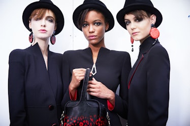 Three female models posing in black dresses while wearing black bucket hats