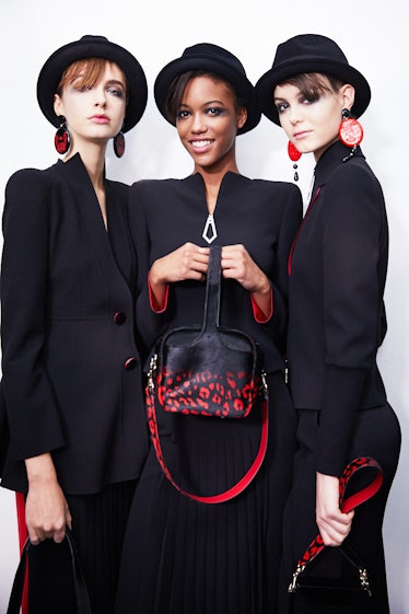 Three female models posing for a photo while wearing black blazers and black hats