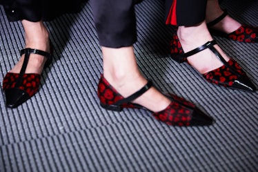 Two ladies that are wearing red and black heel shoes 