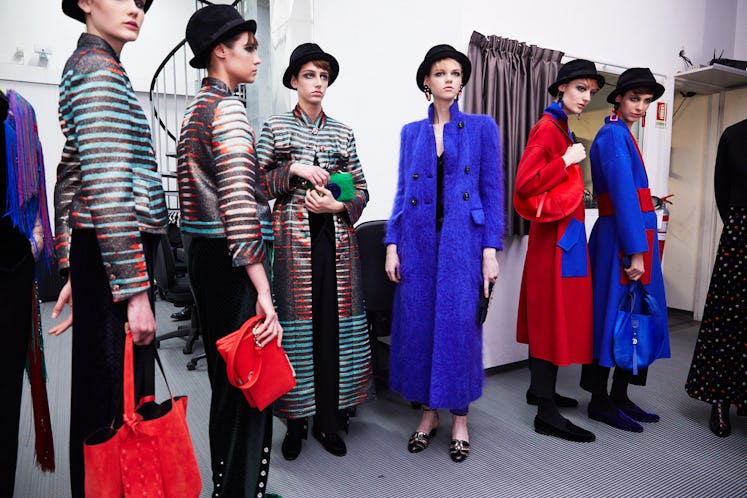 Six models with black hats standing next to each other 
