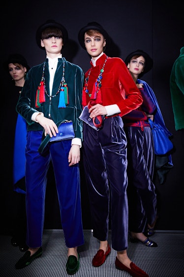 Two models, one in a red sweater, the other in a blue blazer, and both in dark blue pants