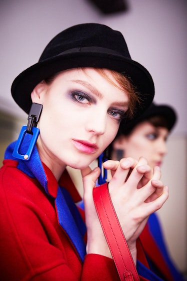 A model posing in a black hat and red and blue blazer