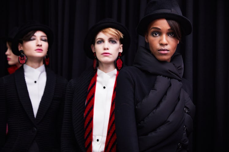 Two ladies wearing black blazers and white shirts and another lady wearing a black coat jacket 