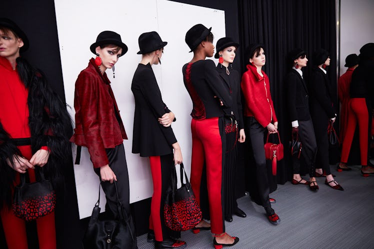 Nine female models standing in a queue while wearing red and black outfits