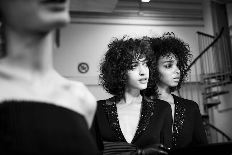 Two curly-haired models posing in black blazers
