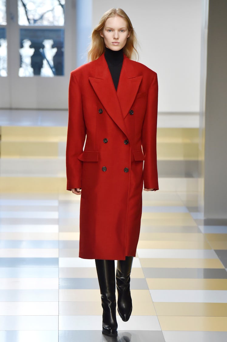 A female model walking in a red coat designed by Jil Sandler