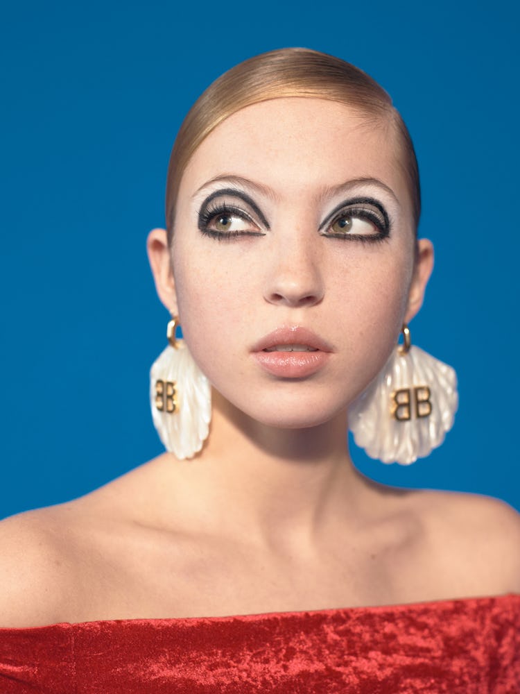 A model wearing white scallop shell earrings and a red off-shoulder top