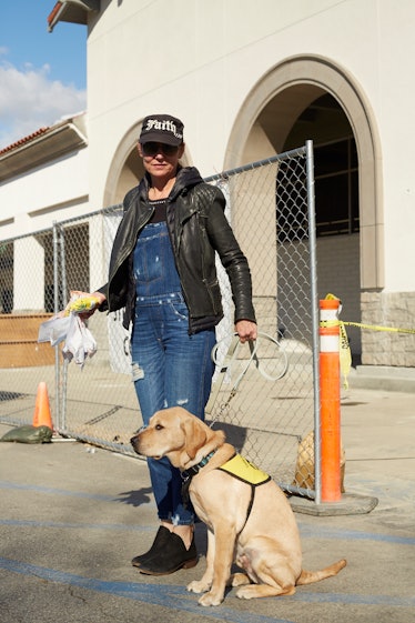 A woman wearing a denim overall and a black leather jacket while taking her dog out
