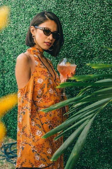 A woman in an orange floral dress holding her drink at Veuve Clicquot’s Third Annual Carnaval party ...