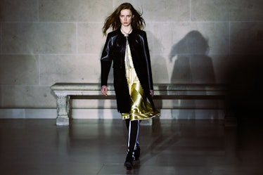A model in a yellow slip dress and a black leather coat walking the runway for Louis Vuitton’s Fall ...