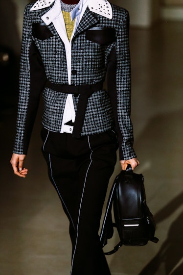A model wearing Louis Vuitton’s Fall 2017 black pants and a plaid belted blazer with white leather s...
