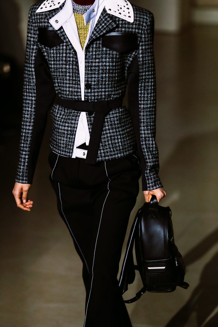 A model wearing Louis Vuitton’s Fall 2017 black pants and a plaid belted blazer with white leather s...