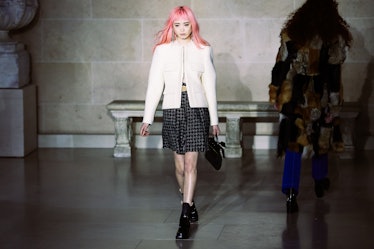 A model wearing a white tweed jacket and a plaid skirt walking the runway for Louis Vuitton’s Fall 2...