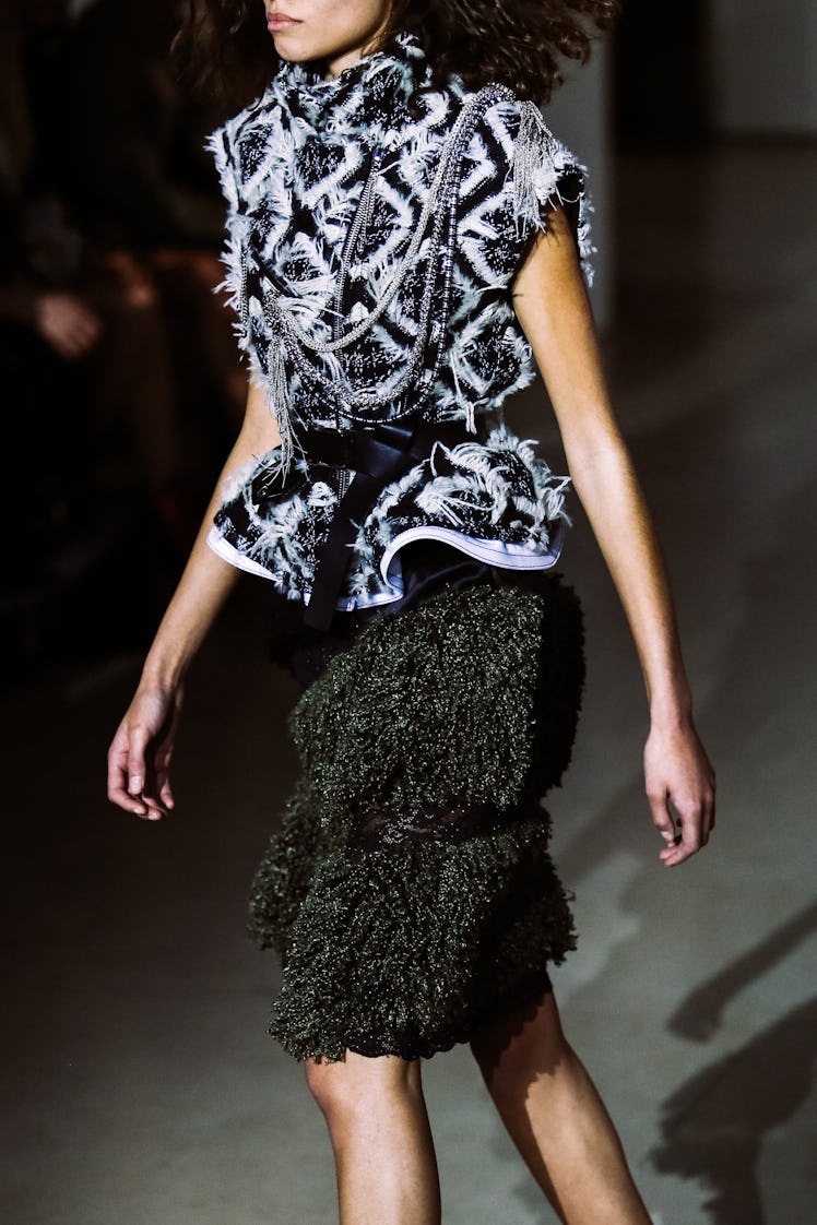 A model wearing a dark green teddy skirt and a black-and-white peplum top from Louis Vuitton’s Fall ...