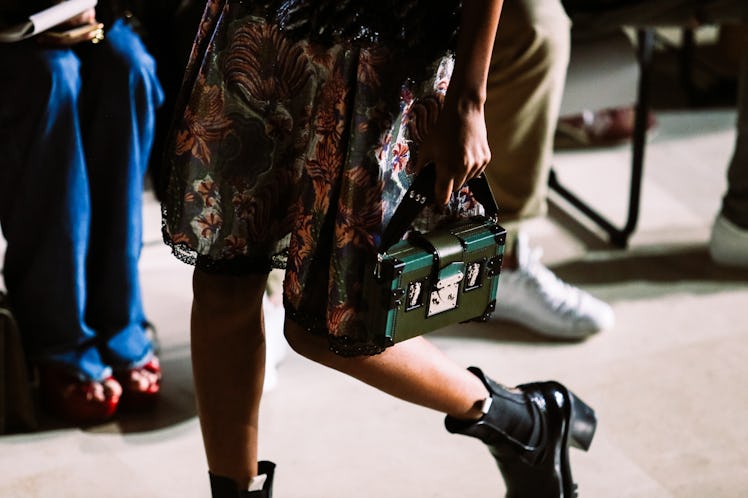 A model in a floral dress holding a bag from Louis Vuitton’s Fall 2017 collection during a fashion s...