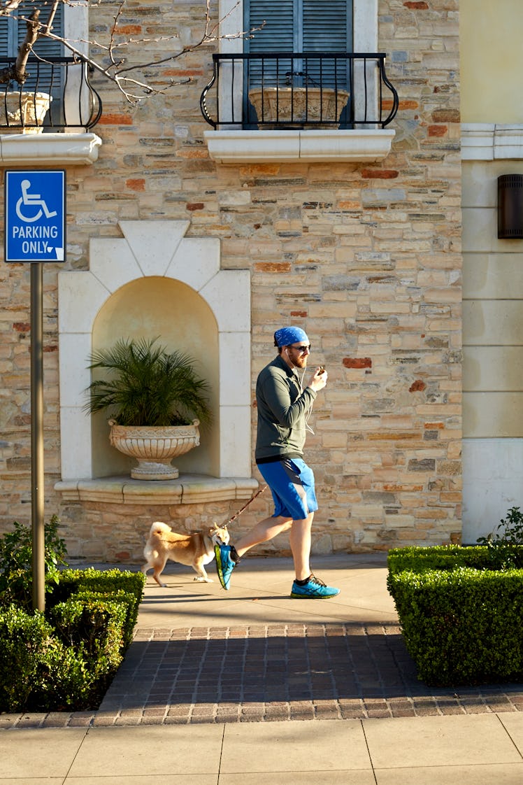 A man casually dressed walking his dog while talking on the phone in Calabasas