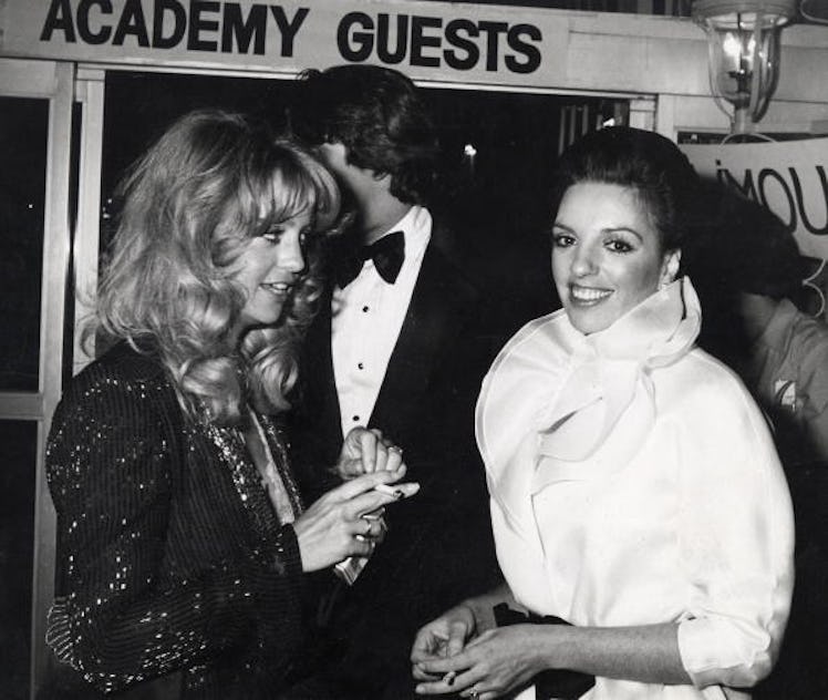 Goldie Hawn, Liza wears high collared white blouse that is cinched at the waist with a black bow.
