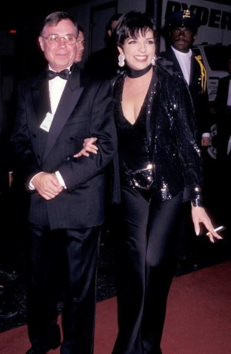 Liza wears all black look with deep cut top, wide legged pants, and a sequin blazer 