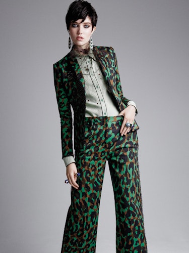 A female model posing in a green snake print blazer and pants on St. Patrick’s Day