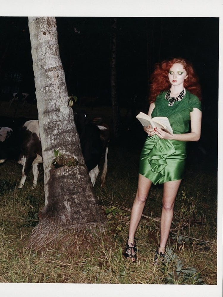 A woman standing in a green dress next to cows in dark on St. Patrick’s Day
