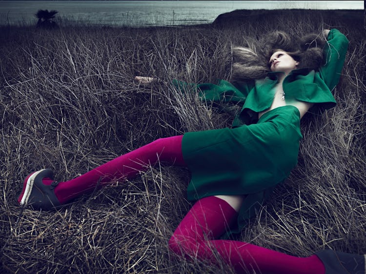 A woman lying in a bed while wearing a green blazer and skirt on St. Patrick’s Day