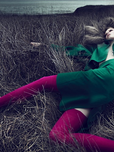 A woman lying in a bed while wearing a green blazer and skirt on St. Patrick’s Day