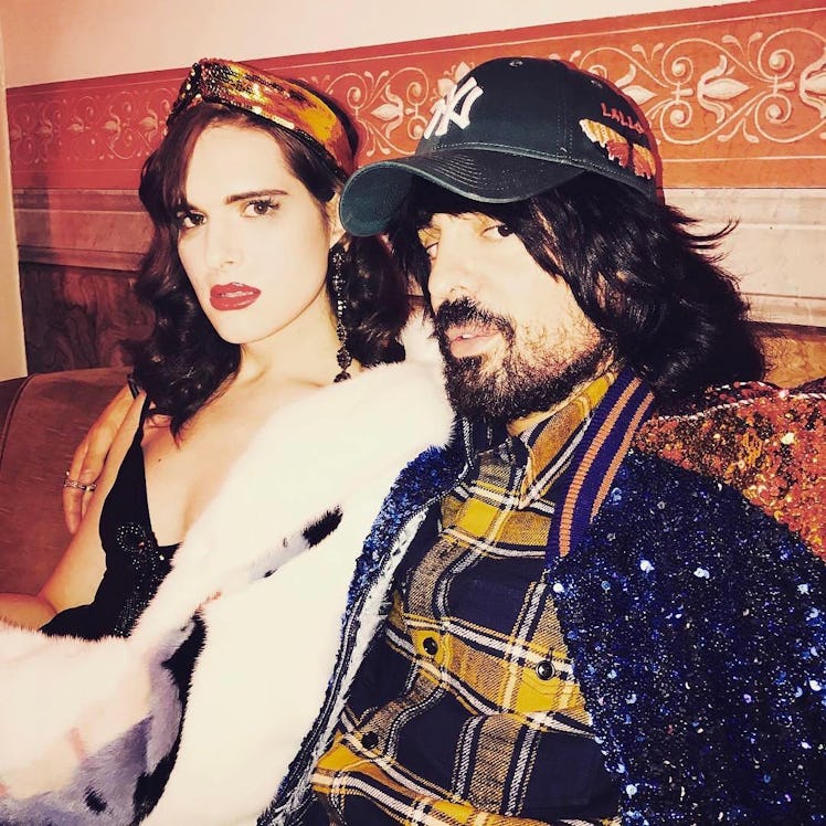 Hari Nef posing with a woman in a Gucci outfit and a Yankees cap 
