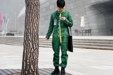 A man in a green jumpsuit with zebra print standing in the street during the Seoul Fashion Week