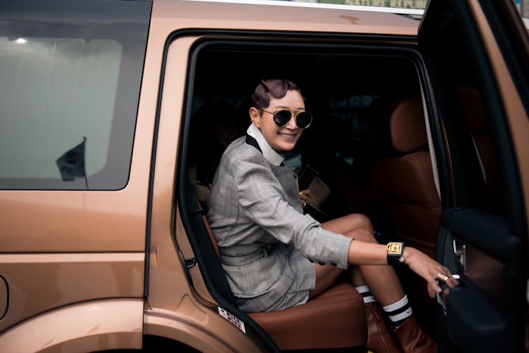 A woman wearing a grey skirt suit and a pair of shades getting out of her car during Seoul Fashion W...
