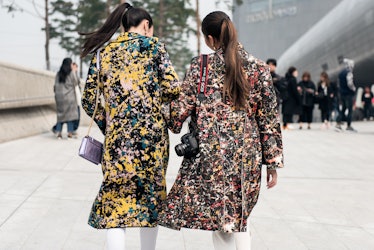 Two women wearing matching coats in different colors during Seoul Fashion Week.